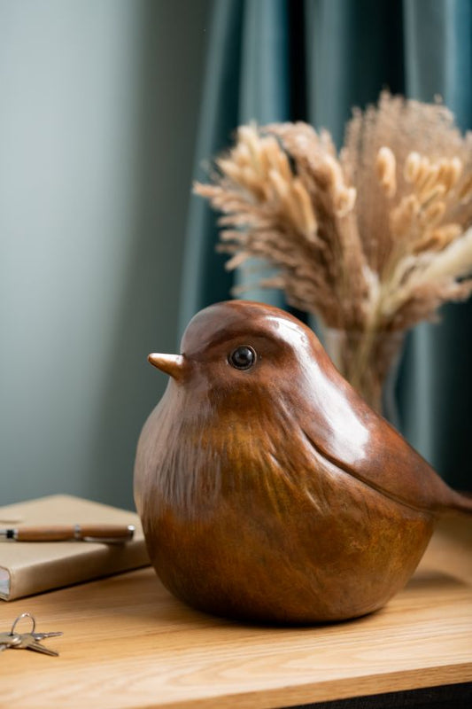 Bronze Robin Sculpture on a wooden surface, with a notebook, pen, and keys nearby