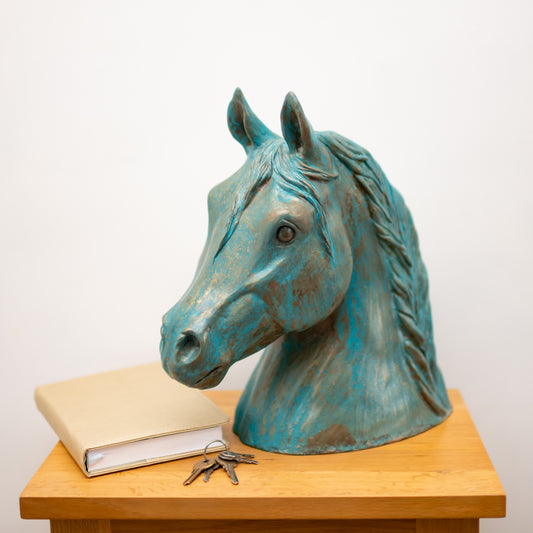 Bronze Horse Head Sculpture with a book and keys on a wooden table