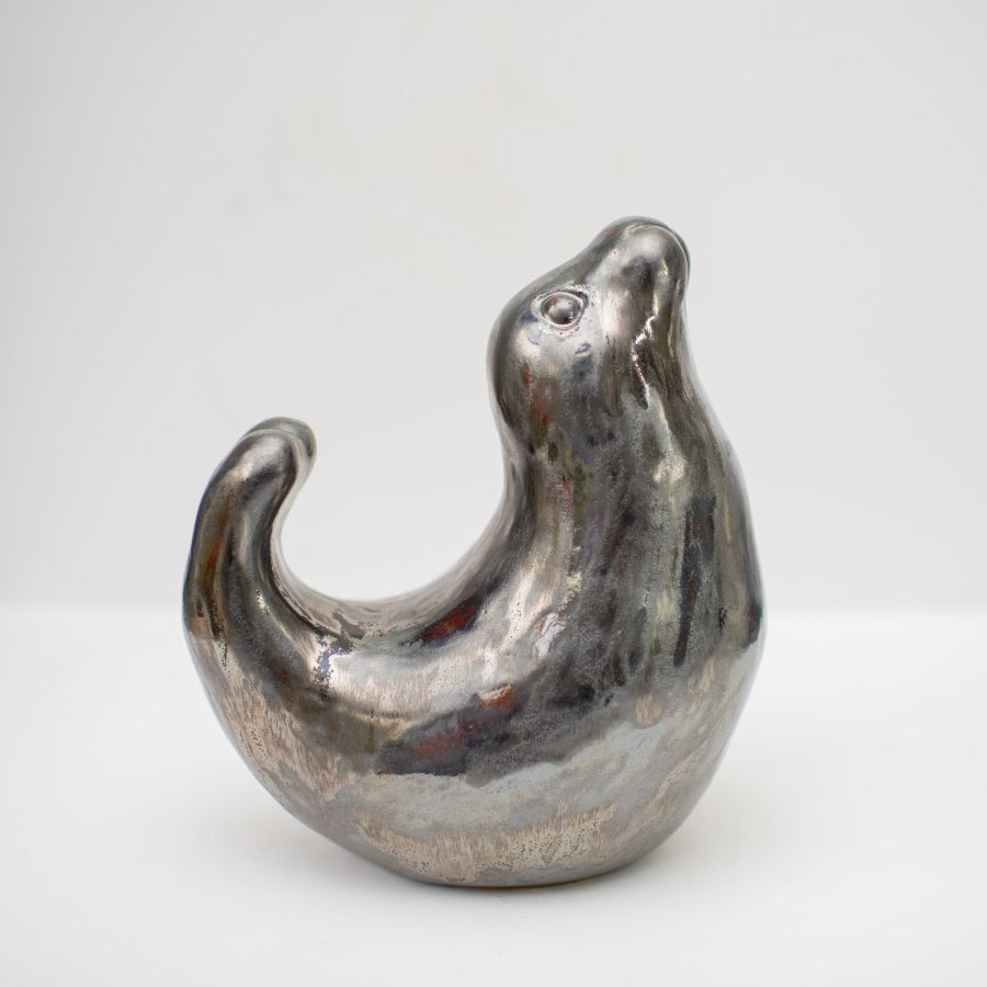 Ceramic seal sculpture in a metallic glaze. They're bent like a banana showing the flexibility and curves of seals