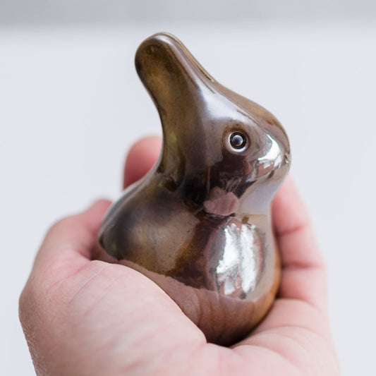Metallic brown glaze baby bunny sculpture in a hand