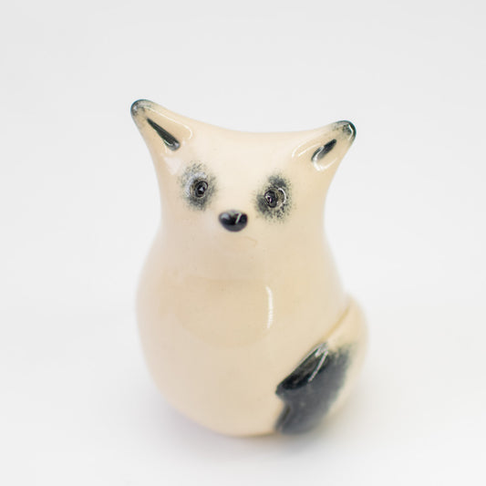 Curious Arctic Fox Sculpture, a small ceramic figurine with a light body and dark eyes, nose, and ear tips
