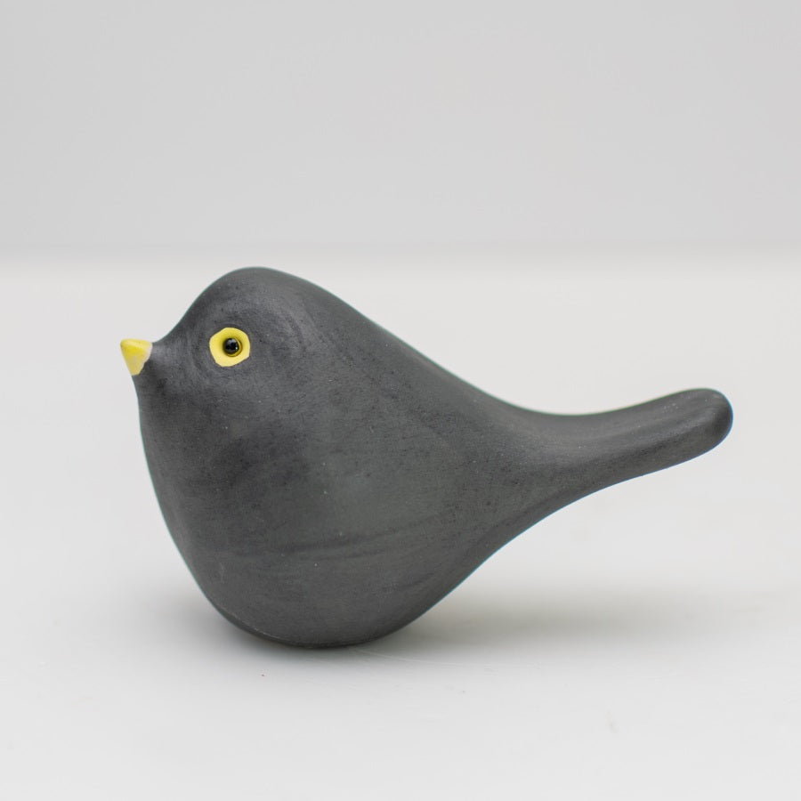Small ceramic blackbird collectable sculpture on a plain background