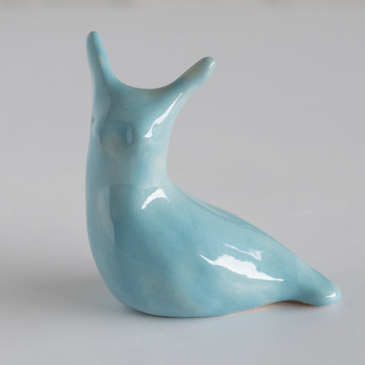 Joyful Light Blue Ceramic Slug, a glossy light blue slug figurine with two antennae, facing left