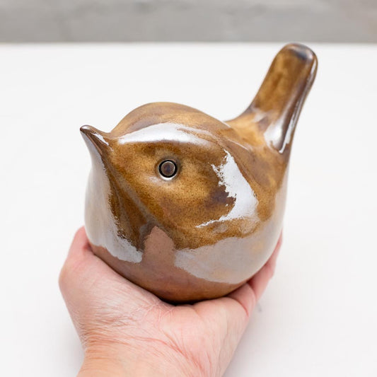 Hand holding a medium ceramic wren sculpture, brown with a glossy finish