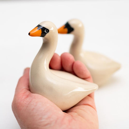 Small Ceramic Swan Sculpture Gift Set held in a hand, with another swan sculpture in the background