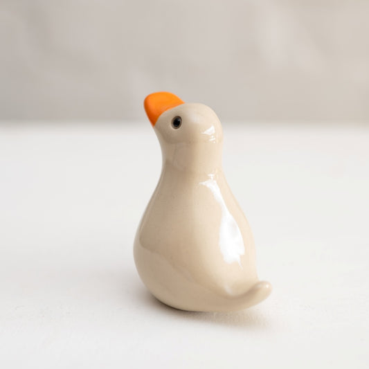 Small Ceramic Duck Sculpture with a beige body and orange beak
