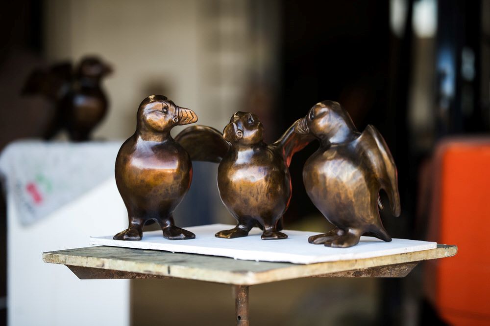 Three bronze Puffin sculptures on a table