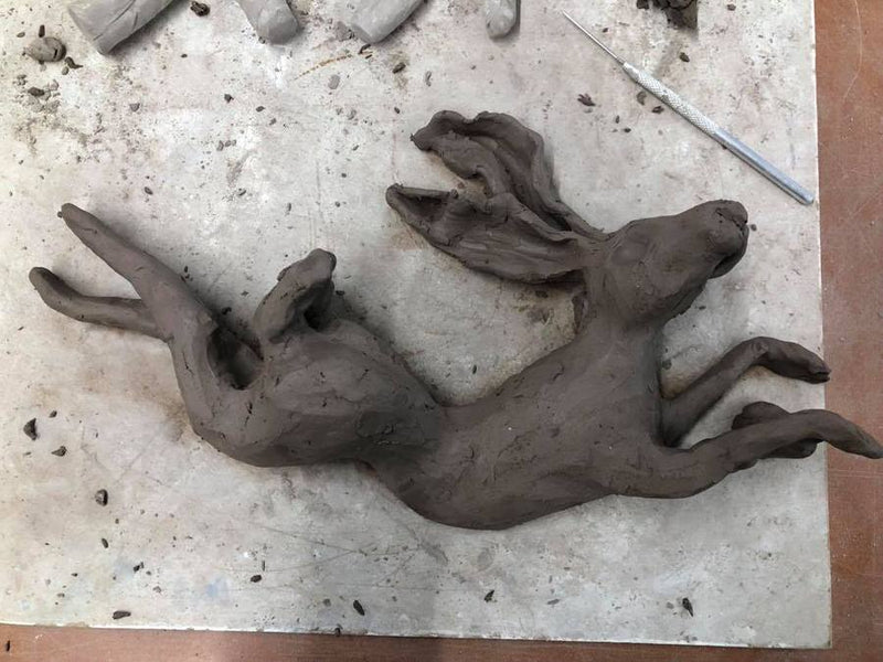a clay sculpture of a leaping hare
