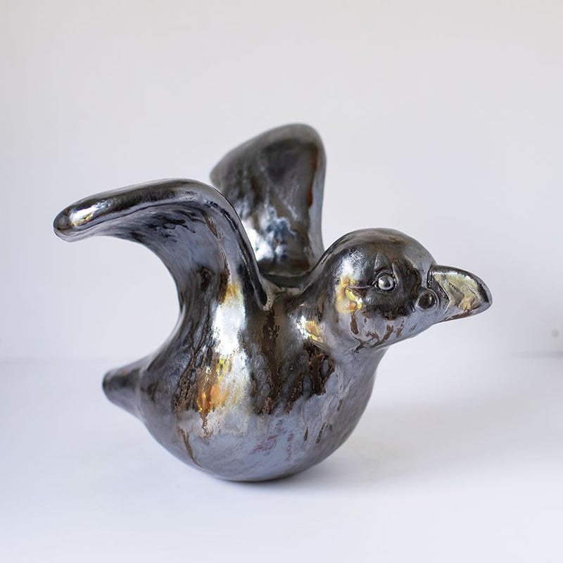 Ceramic Puffin sculprture in a metallic glaze with the wings outstretched