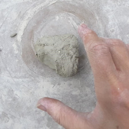 My hand reaching for a lump of clay while making critters