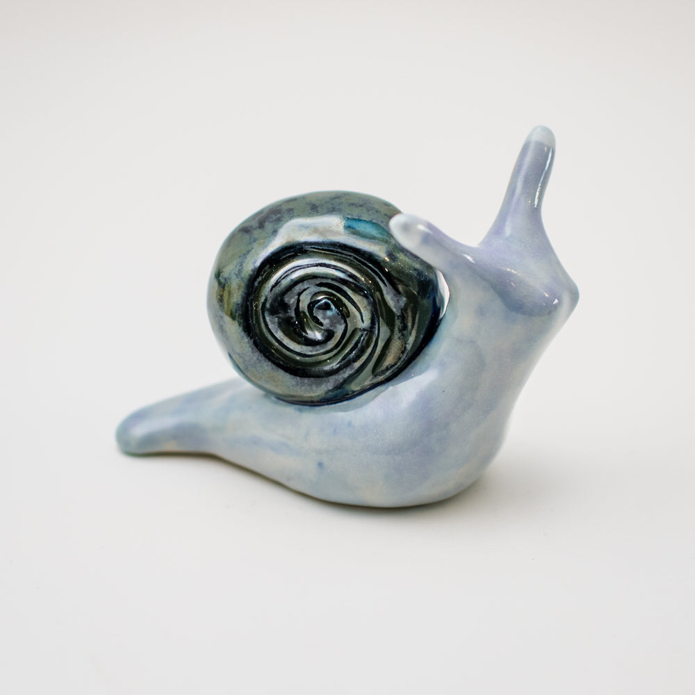 Ceramic snail sculpture in blues on a white background