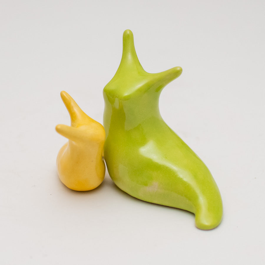 A pair of yellow and green ceramic slugs on a white background