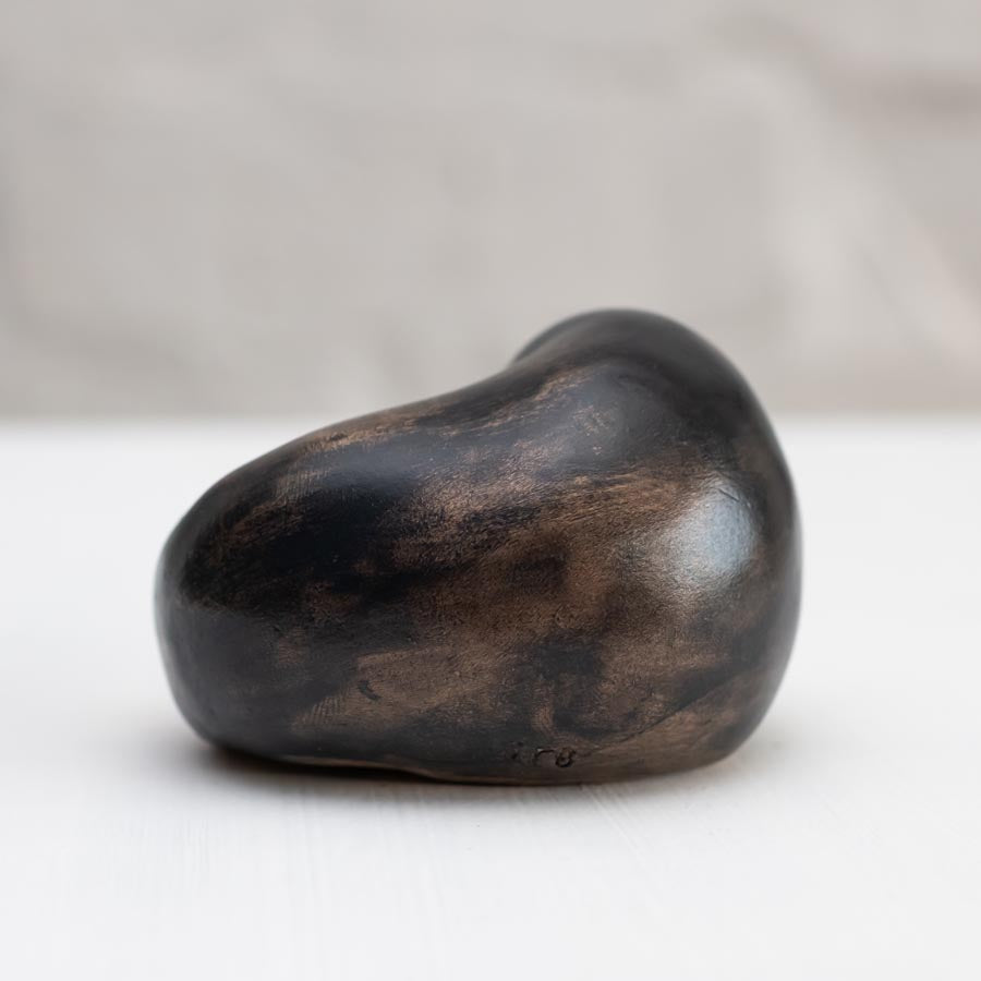 Small bronze sculpture of a badger curled up asleep against a white background - rear view