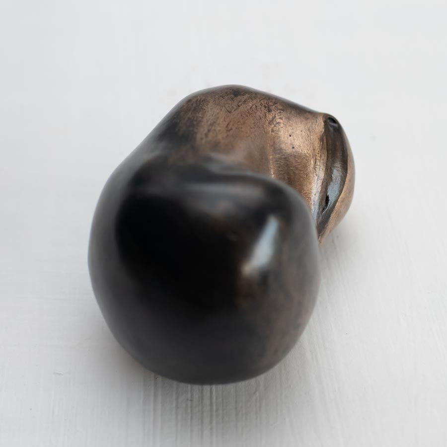 Small bronze sculpture of a badger curled up asleep against a white background