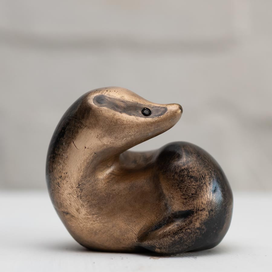 A small bronze badger sculpture against a white background