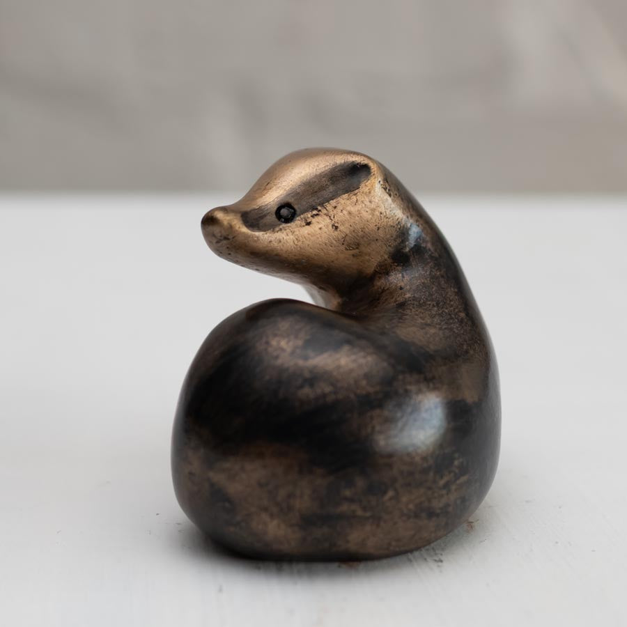 A small bronze badger sculpture against a white background