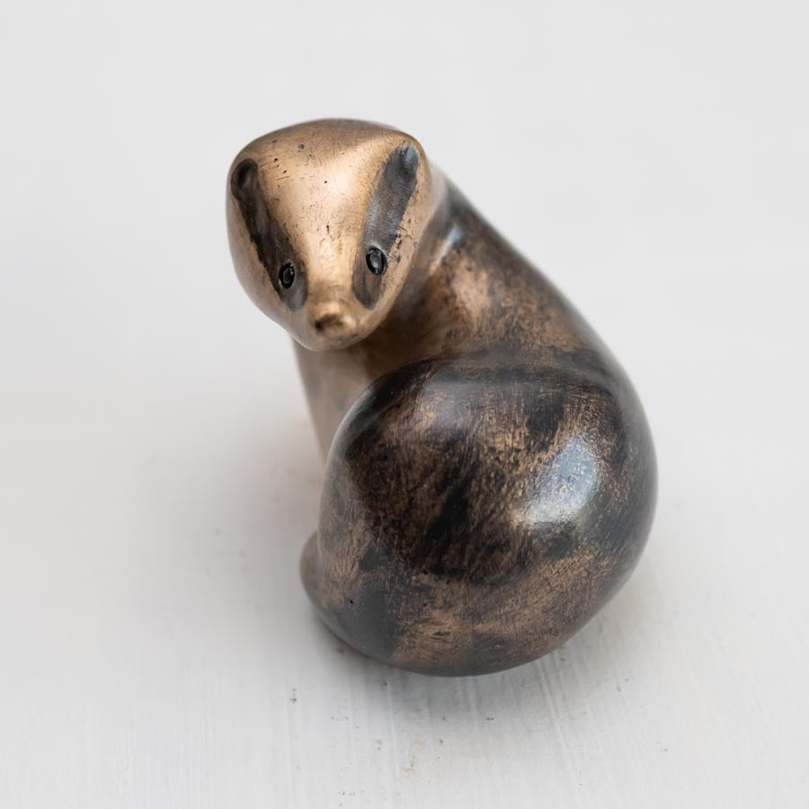 A small bronze badger sculpture against a white background