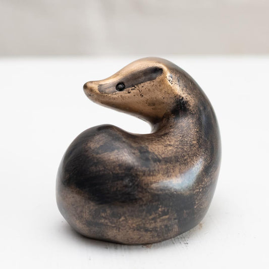 A small bronze badger sculpture against a white background