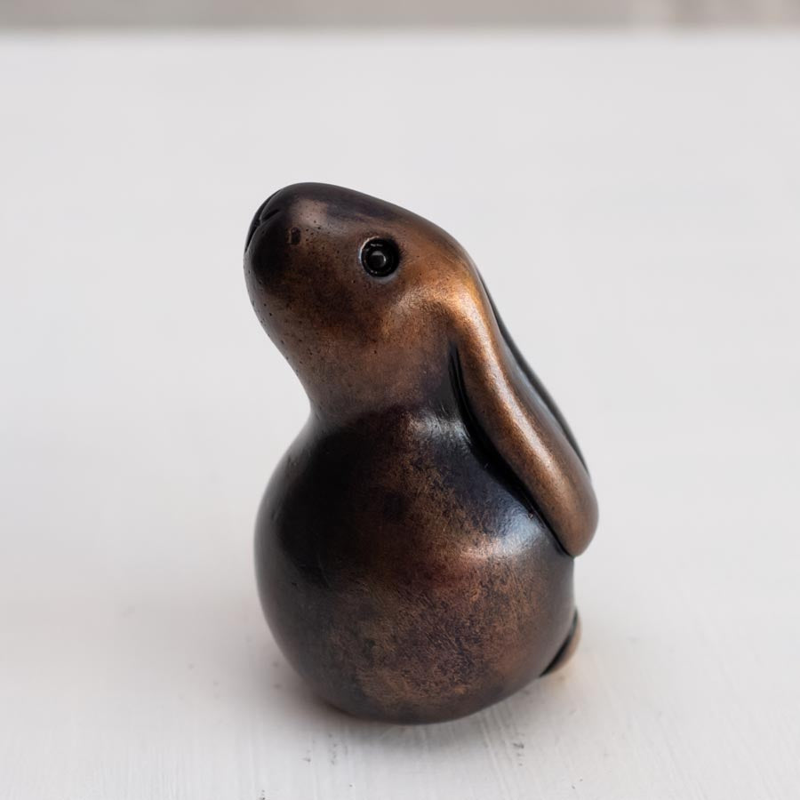 Brown bunny rabbit sculpture in bronze against a white background