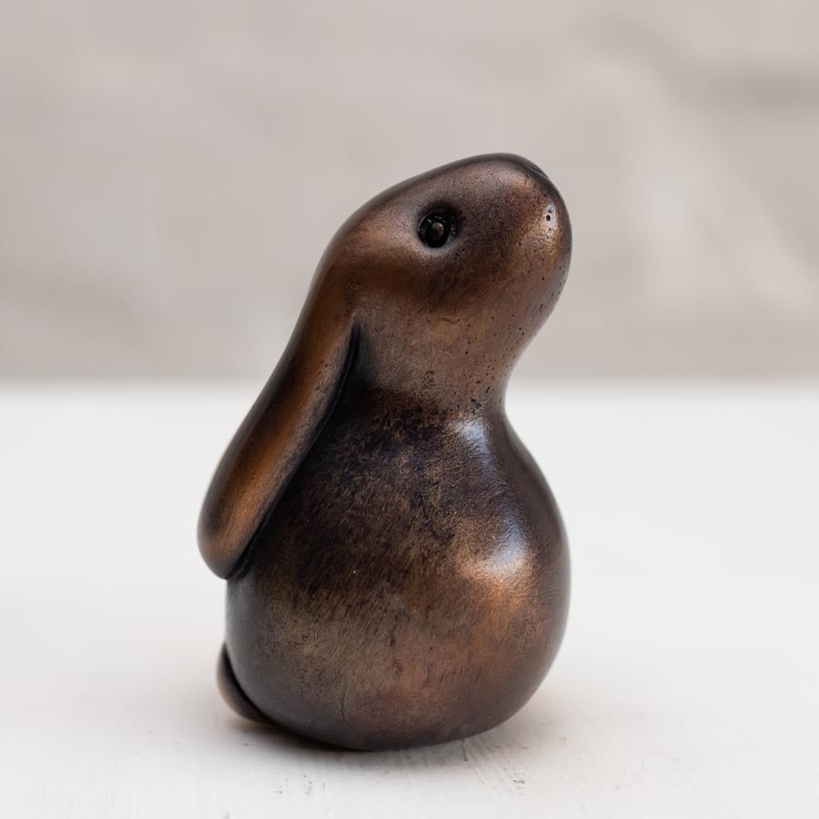 Brown bunny rabbit sculpture in bronze against a white background