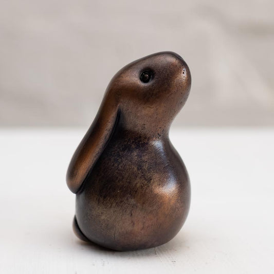 Brown bunny rabbit sculpture in bronze against a white background
