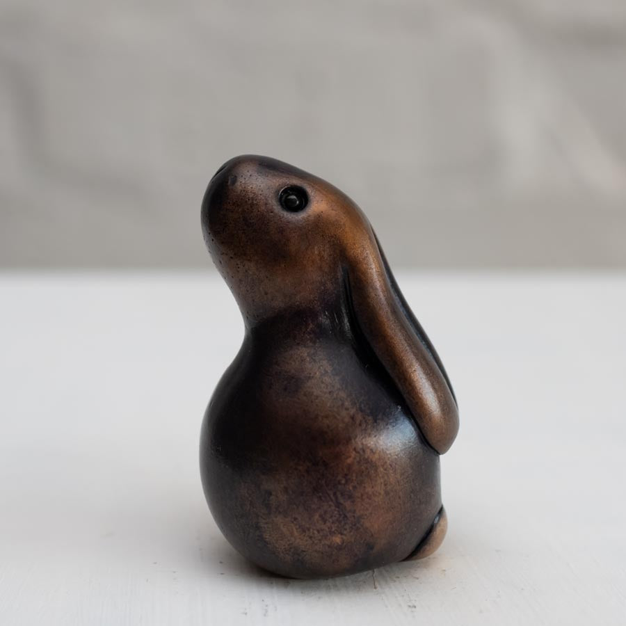 Brown bunny rabbit sculpture in bronze against a white background