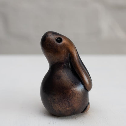 Brown bunny rabbit sculpture in bronze against a white background
