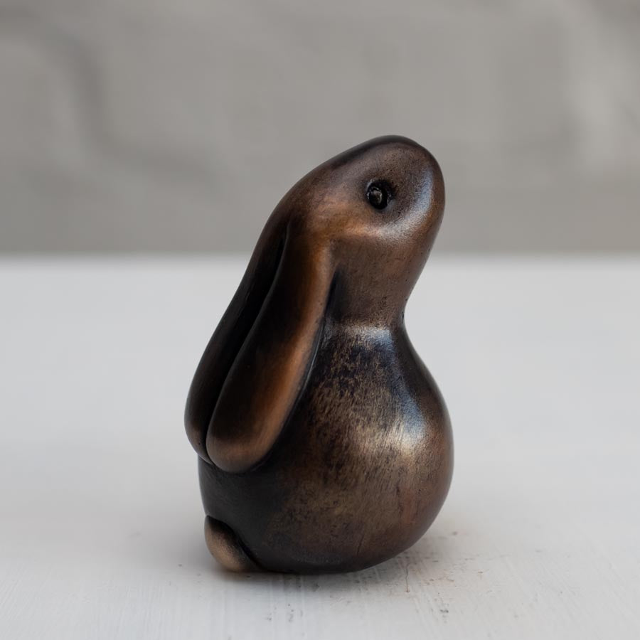 Brown bunny rabbit sculpture in bronze against a white background