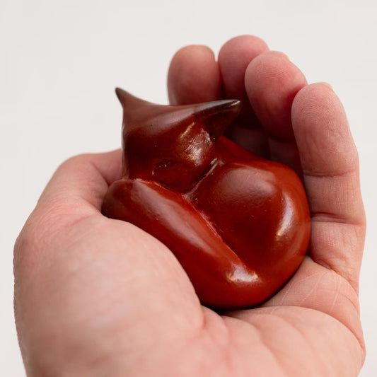 Small foundry bronze fox sculpture held in a person's palm