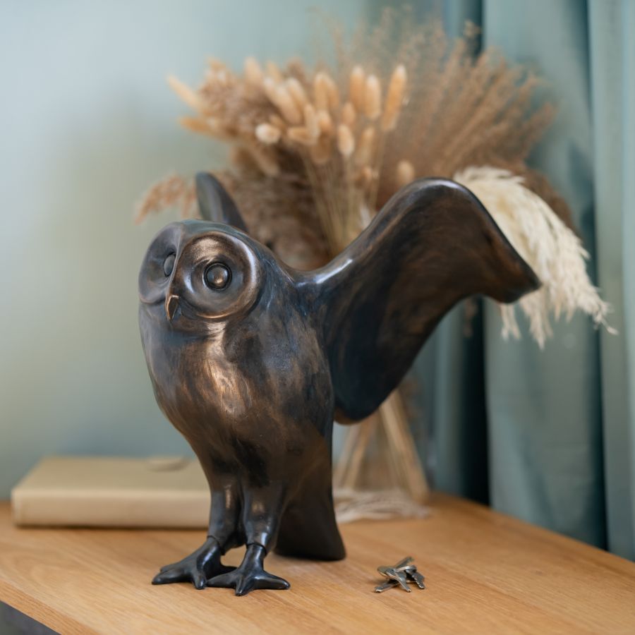 Large Bronze Owl Sculpture with outstretched wings on a wooden surface