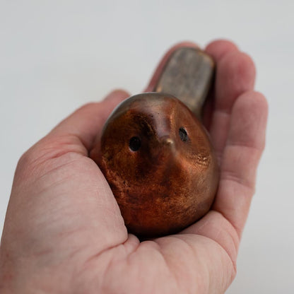 A small bronze robin sculpture on a hand against a white background