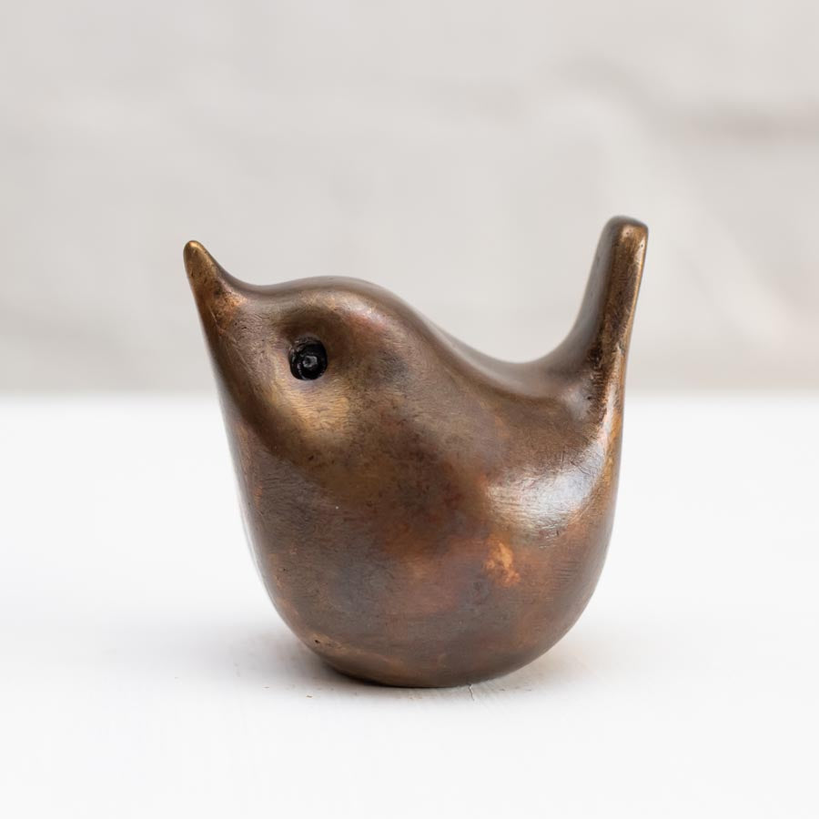 Small bronze wren sculpture against a white background