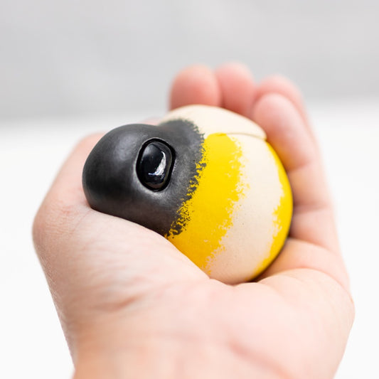 Ceramic Bumblebee Sculpture held in a hand, black head with a shiny eye, yellow and cream striped body