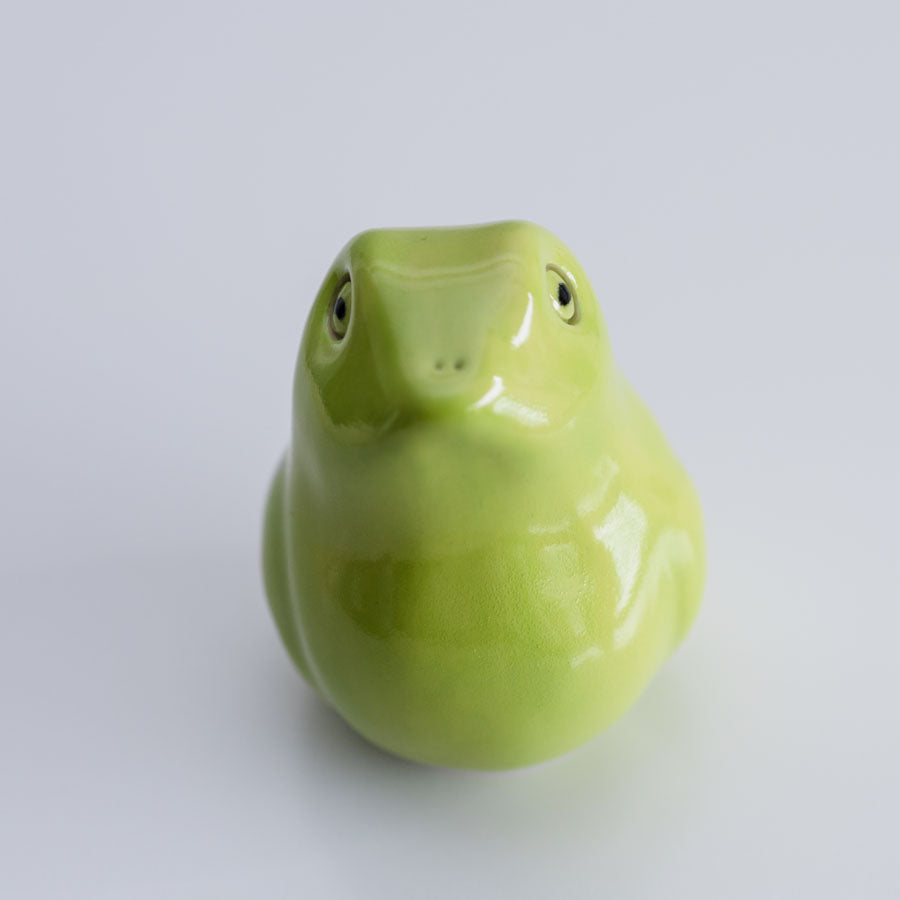 A glossy light green ceramic frog figurine photographed against a seamless light gray background.