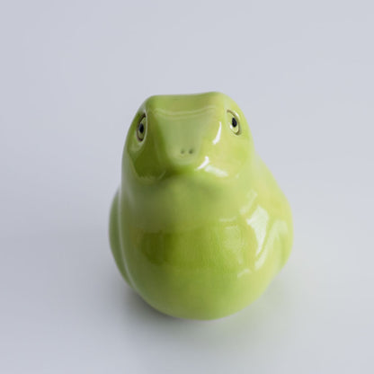 A glossy light green ceramic frog figurine photographed against a seamless light gray background.