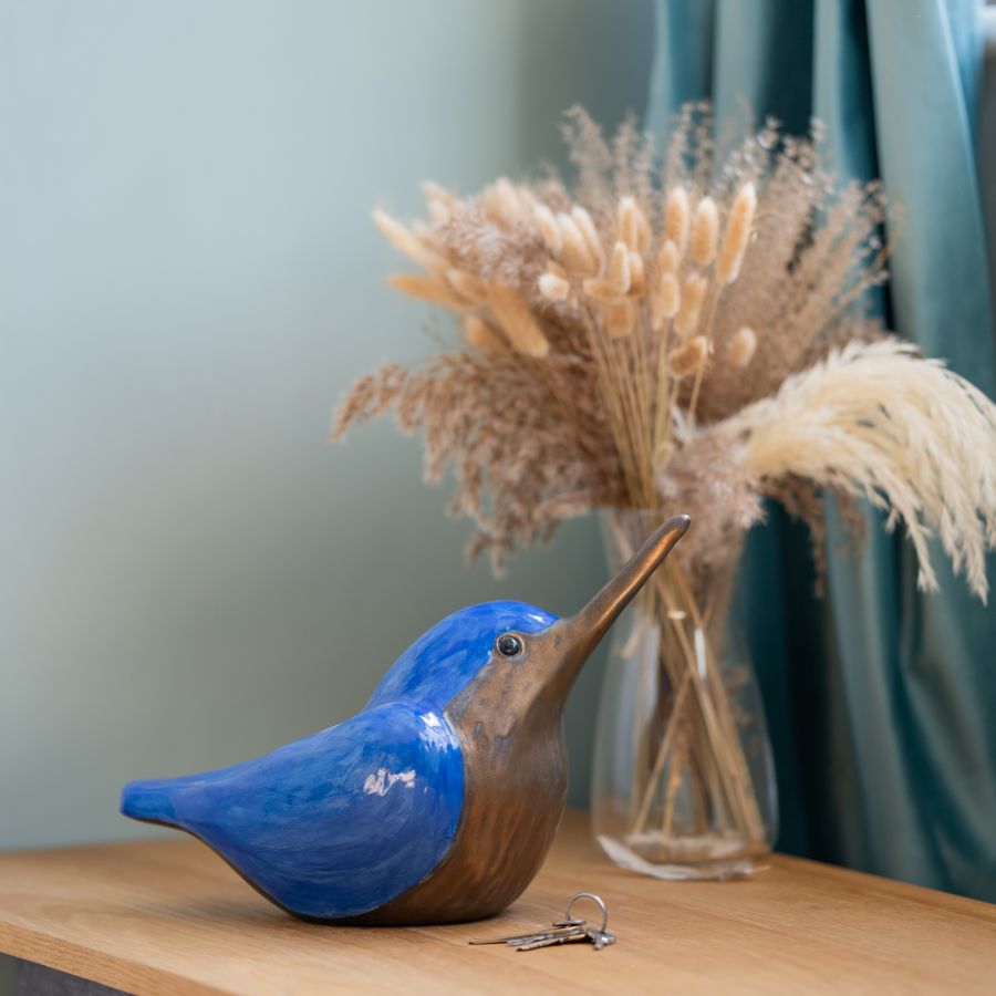 Clay Kingfisher Sculpture, blue and bronze, on a wooden surface with keys and dried flowers