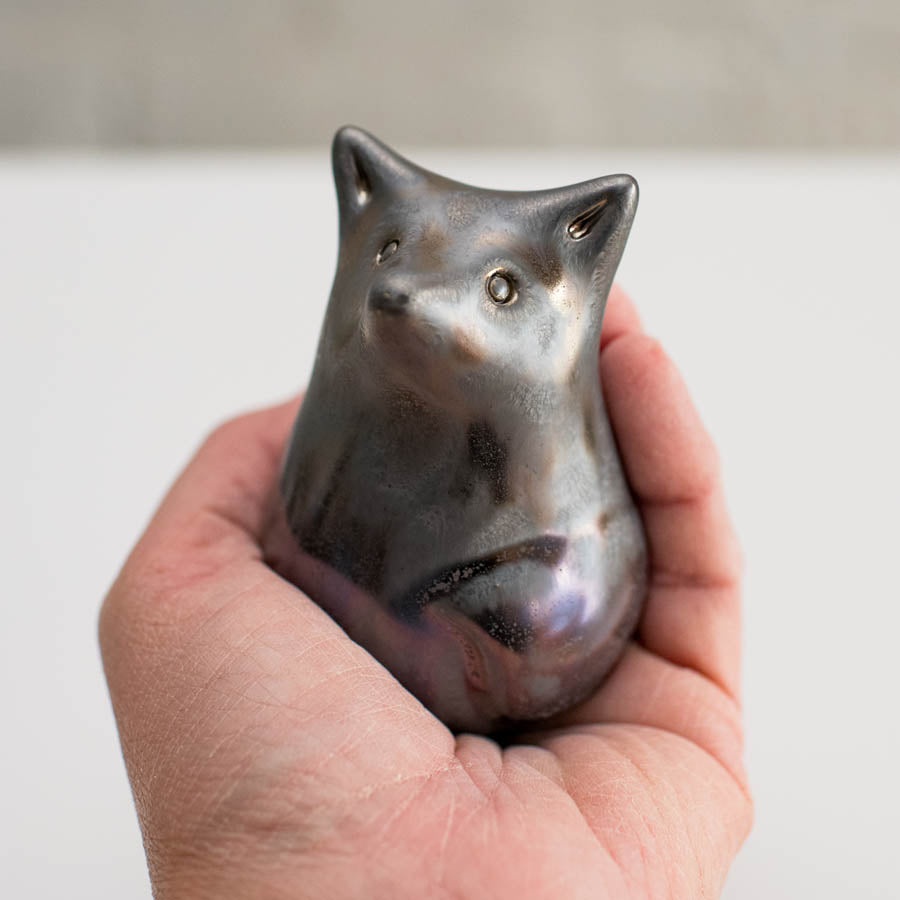 Silver fox ceramic sculpture in a hand