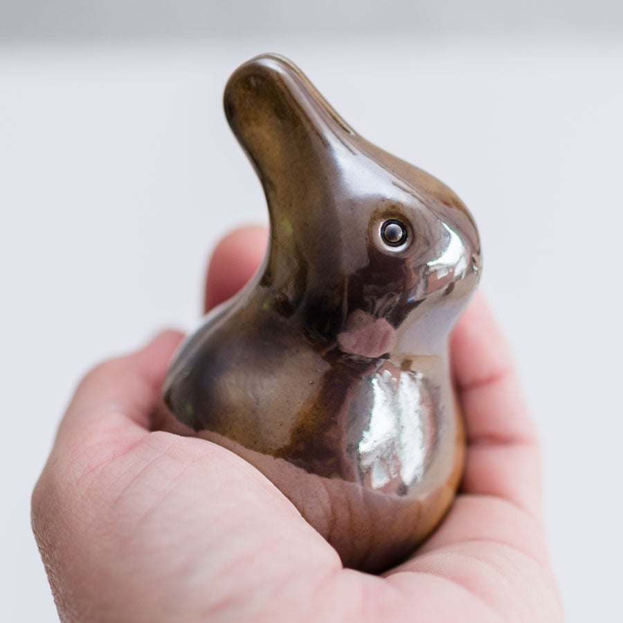 Metallic brown glaze baby bunny sculpture in a hand