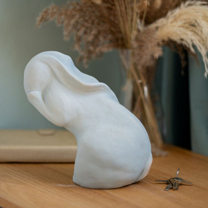 Washing my Hare Sculpture, a white ceramic hare with its head tilted back, on a wooden surface