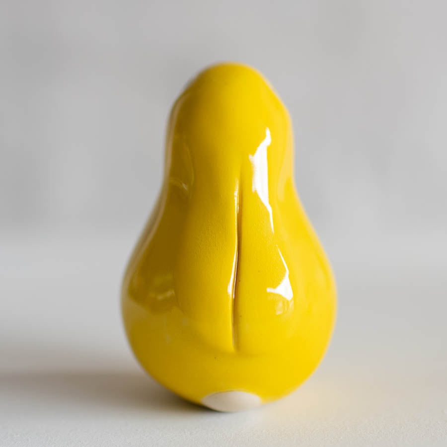 A glossy yellow bunny sculpture standing on a light gray background.