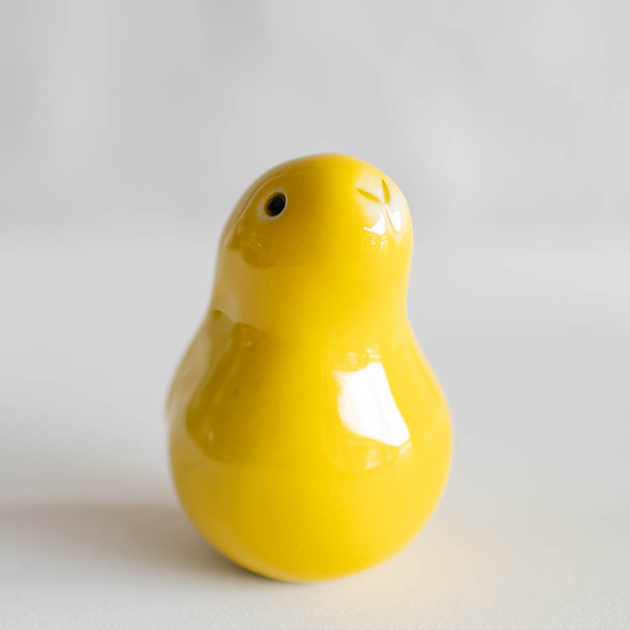 A glossy yellow bunny sculpture standing on a light gray background.