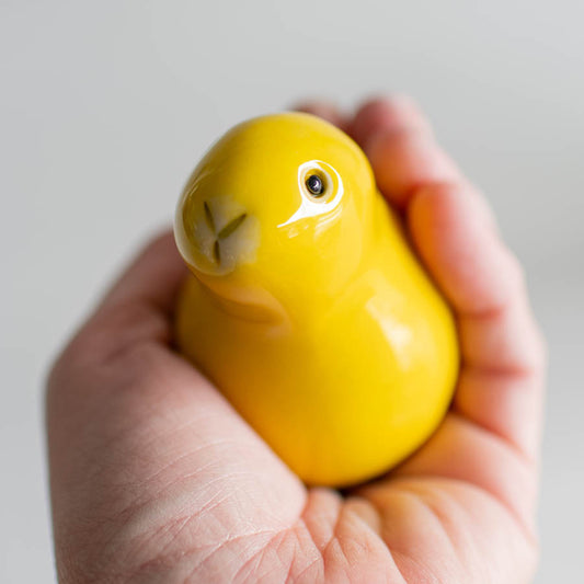 A glossy yellow bunny sculpture in a hand
