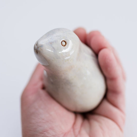 Ceramic hare sculpture in a light glossy glaze in a hand