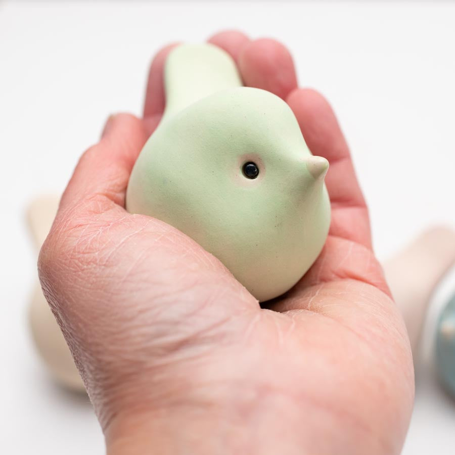 Hand holding a light green Spring Pastel Ceramic Joyful Bird with a small black eye