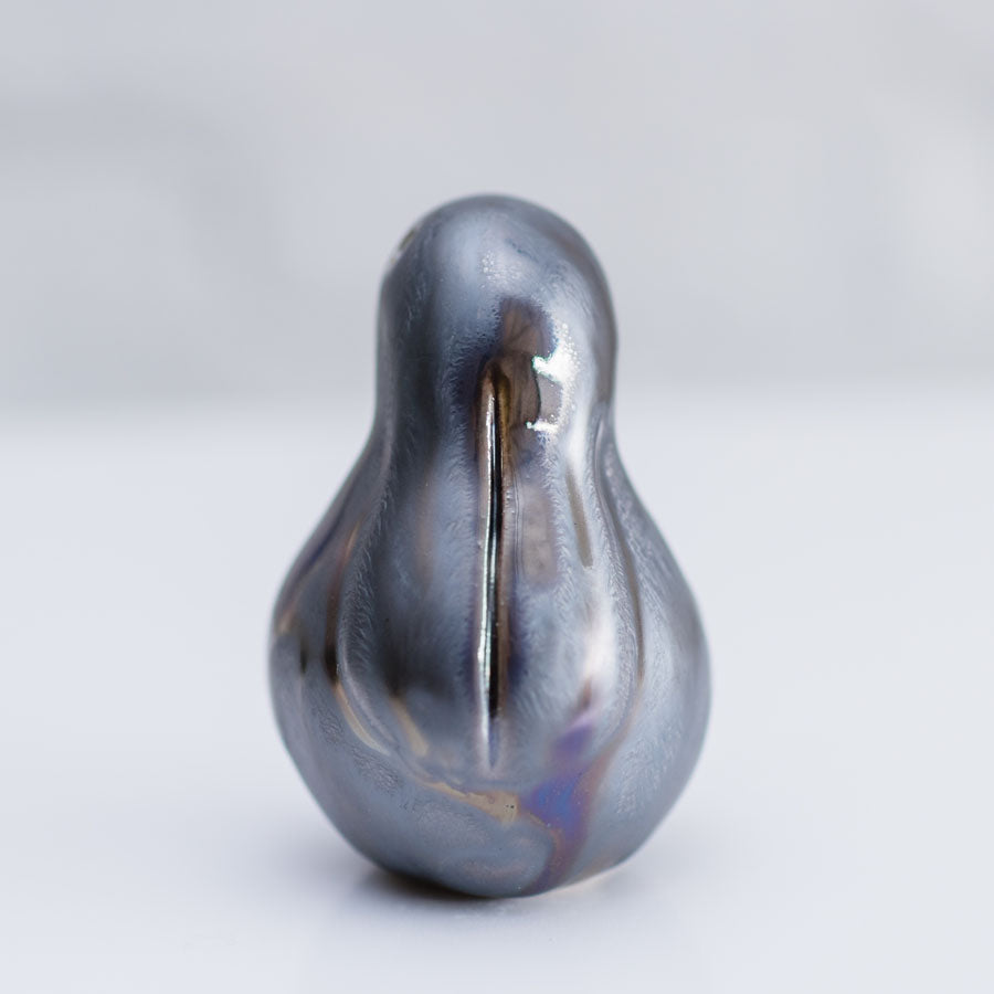 A small sculptural bunny figurine with a glossy, pearlescent dark gray to black finish and subtle iridescent hints, photographed on a clean light gray background.