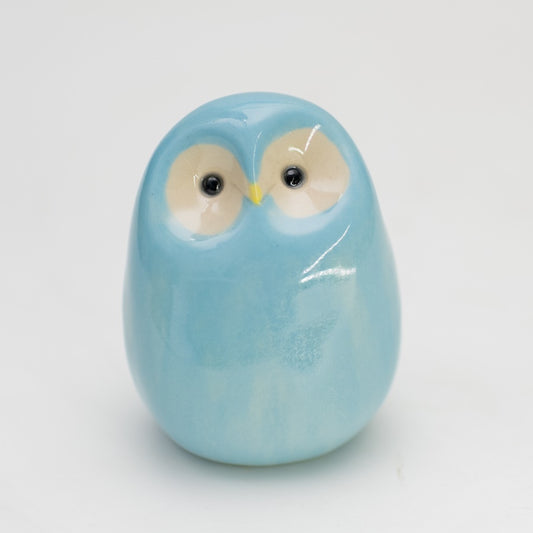 Sky blue, glossy, small ceramic owl with a plain background