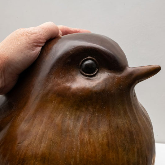 Hand on a bronze Robin sculptures head
