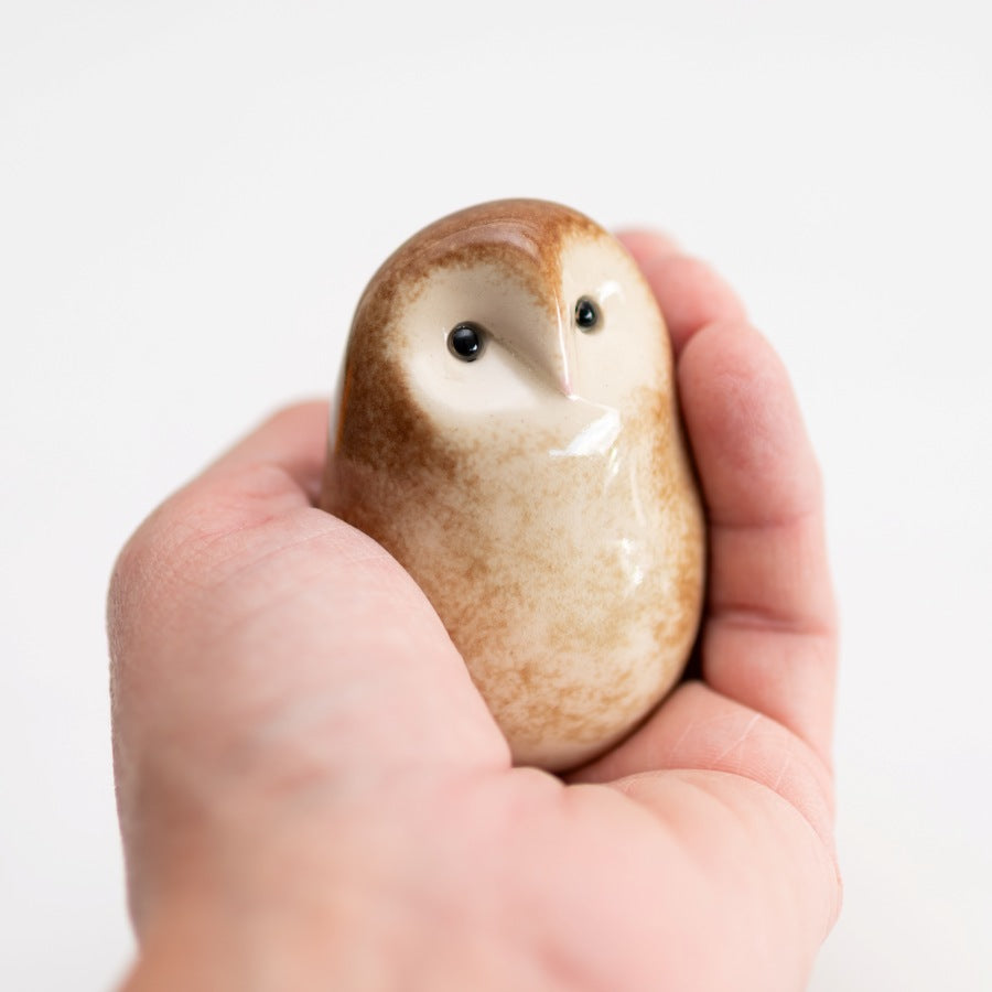 Small ceramic Barn Owl sculpture in a hand against a white background