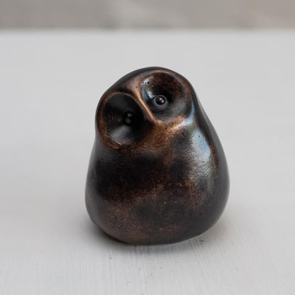 Small smooth bronze owl sculpture on a plain background
