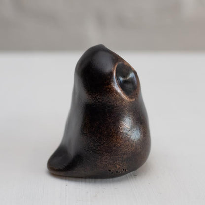 Small smooth bronze owl sculpture on a plain background